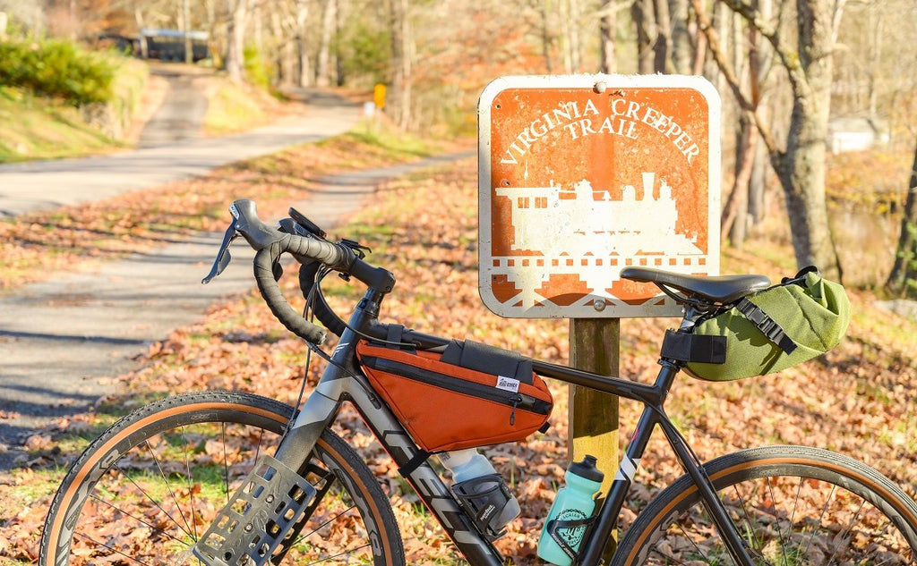 Road Runner Bags Saddle Bags - showing a bike against a trail sign in the fall woods.